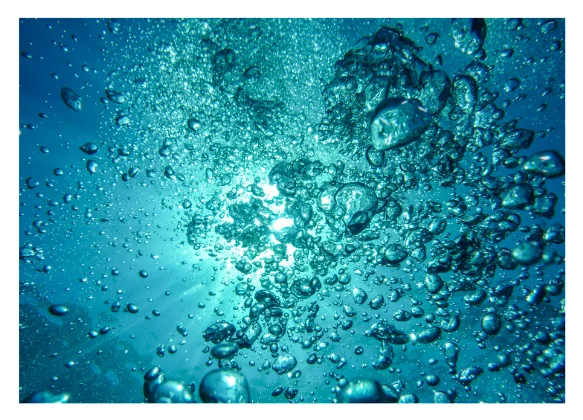 Aufsteigende Luftblasen unter Wasser im Sonnenlicht